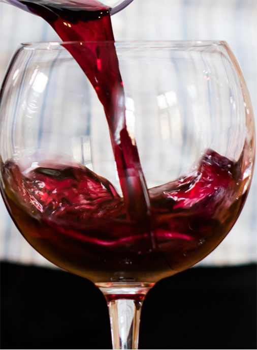 dark red wine being poured into a glass